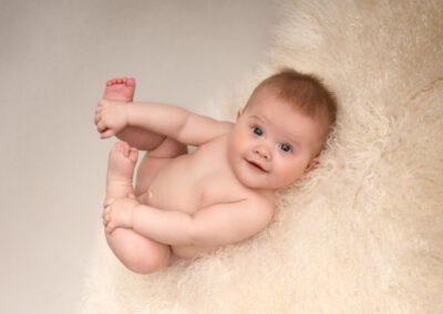 Babyfotografering flicka 6 månader håller i fötterna i studio i Kristianstad när Sölvesborg och Hässleholm