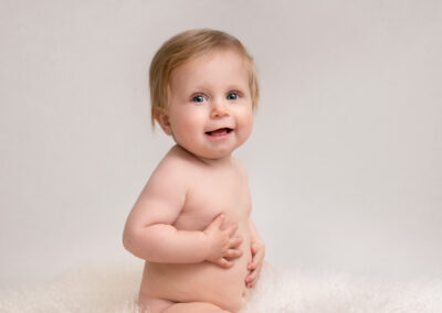 Babyfotografering flicka 10 månader sitter på fäll i fotostudio i Kristianstad Skåne