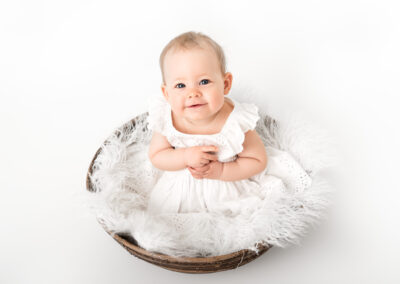 Barnfotografering flicka 9 månader sitter i korg i fotostudio i Kristianstad nära Lund