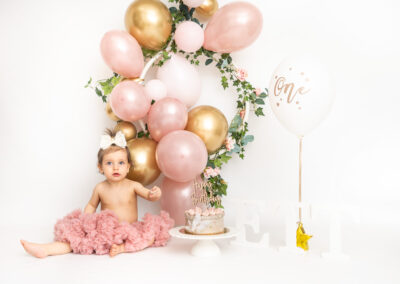 Cakesmash fotografering Ava ett år i tyllkjol med rosa ballonger och tårta i Kristianstad nära Lund och Hässleholm