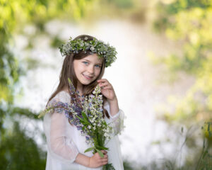 Flicka med krans i håret håller blommor i handen vid en utomhus barnfotografering i Kristianstad nära Sölvesborg och Bromölla