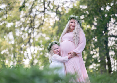Utomhus gravidfotografering med syskon i lånade klänningar och kransar i Kristianstad nära Hässleholm