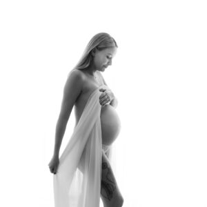 Hudnära gravidfotografering Johanna med draperat tyg och vit bakgrund i studio i Kristianstad nära Lund