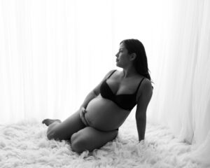 Hudnära Gravidfotografering Matilda sittande med vit bakgrund i studio i Kristianstad nära Hässleholm
