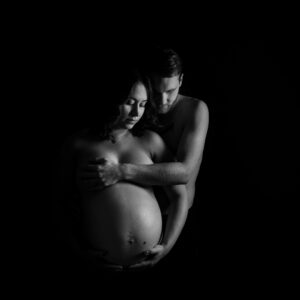 Hudnära gravidfotografering med partner och mycket skuggor i studio i Kristianstad nära Hässleholm