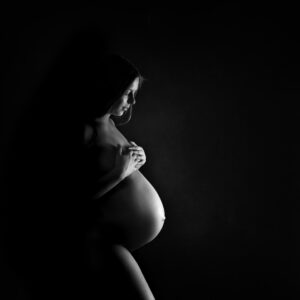 Hudnära Gravidfotografering Emelie med bar mage och mycket skuggor i studio i Kristianstad nära Hässleholm
